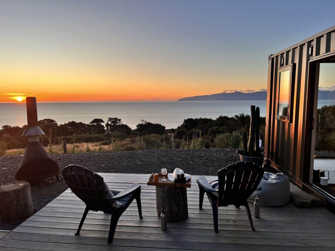 View out to the Cook Strait from a wooden deck with two chairs and a small table on it