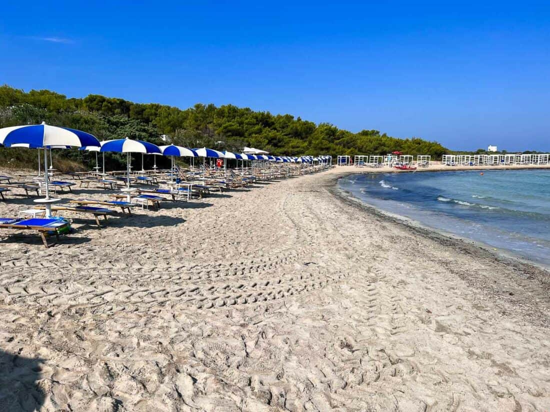 Quiet morning at a lido on Punta Pizzo Beach filled with blue and white sun loungers and parasols, Puglia