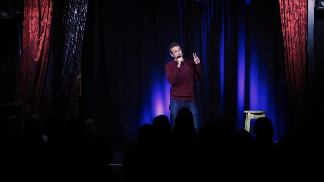 Simon along on a stage holding a microphone