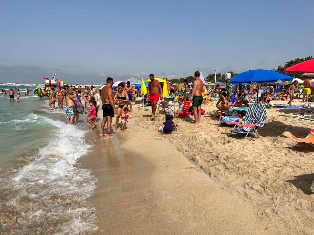 Busy free section of Torre Lapillo Beach in mid August, Puglia