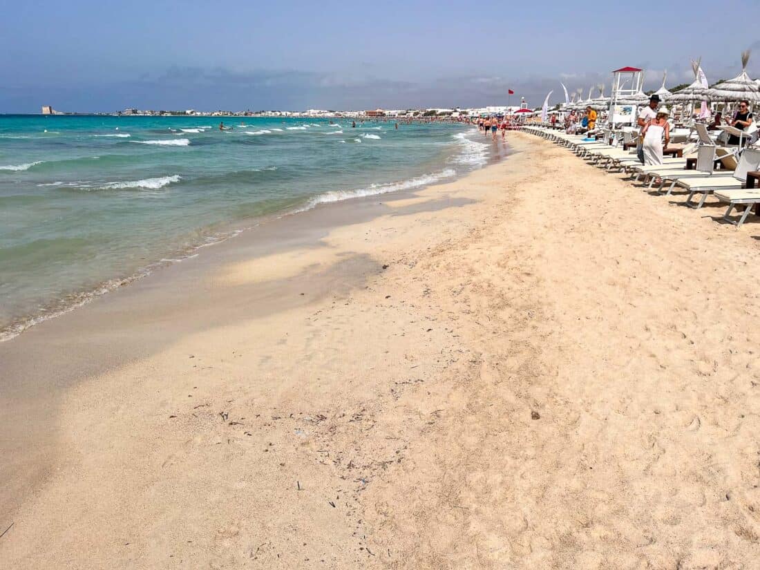 Soft white sand of Torre Lapillo Beach filled with white sun loungers, Puglia, Italy