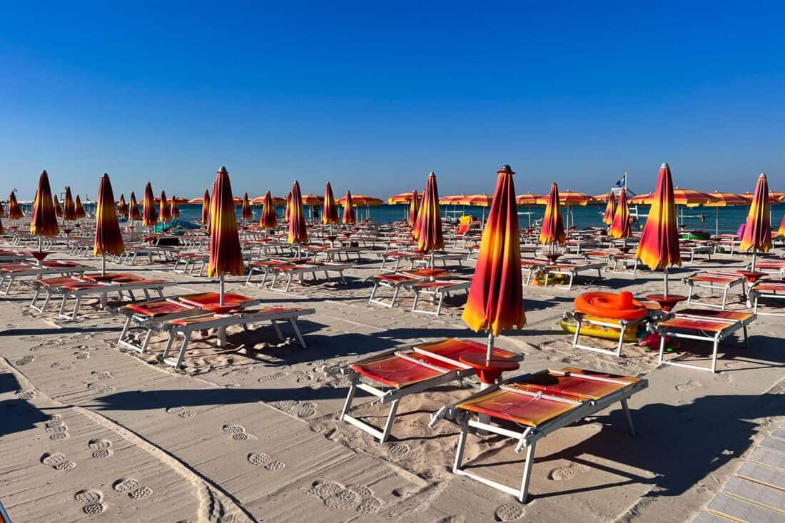 Quiet morning on a Torre San Giovanni beach lido filled with empty sun loungers, Puglia, Italy