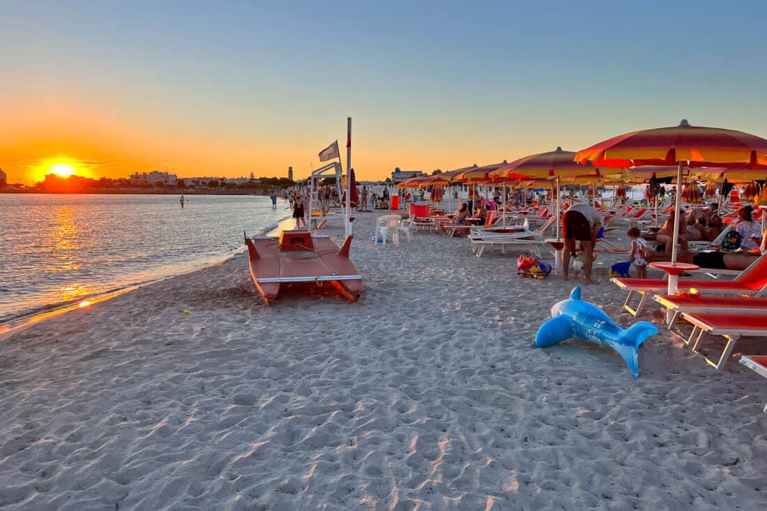 Sunset at Torre San Giovanni beach filled with empty sun loungers and beach toys, Puglia