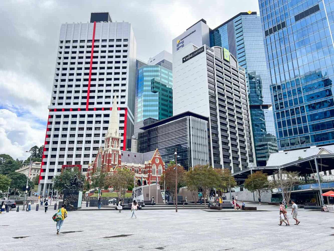 Red-bricked Albert Street Uniting Church in King George Square backed by towering highrises, Brisbane, Australia