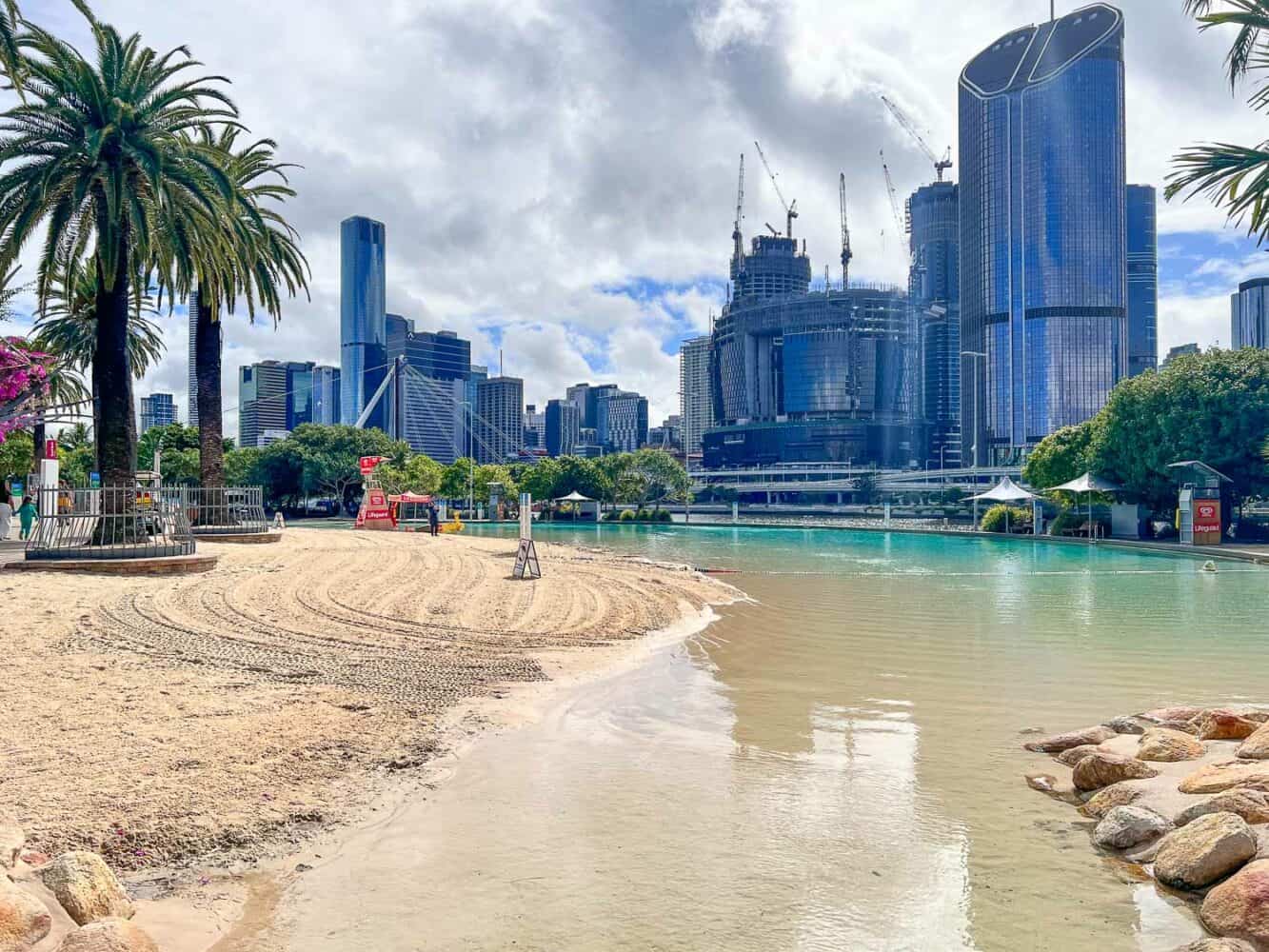 Unique Streets Beach with a shallow clear lagoon, palm trees and glistening skyscrapers, Brisbane, Australia