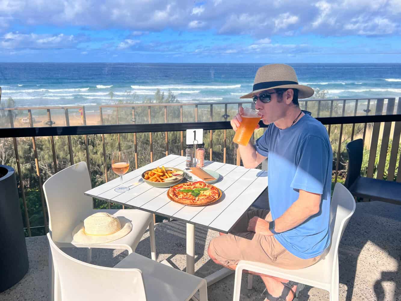 Simon enjoying his pint and pizza by the sea at Sunshine Beach Surf Life Saving Club, Noosa, Queensland, Australia