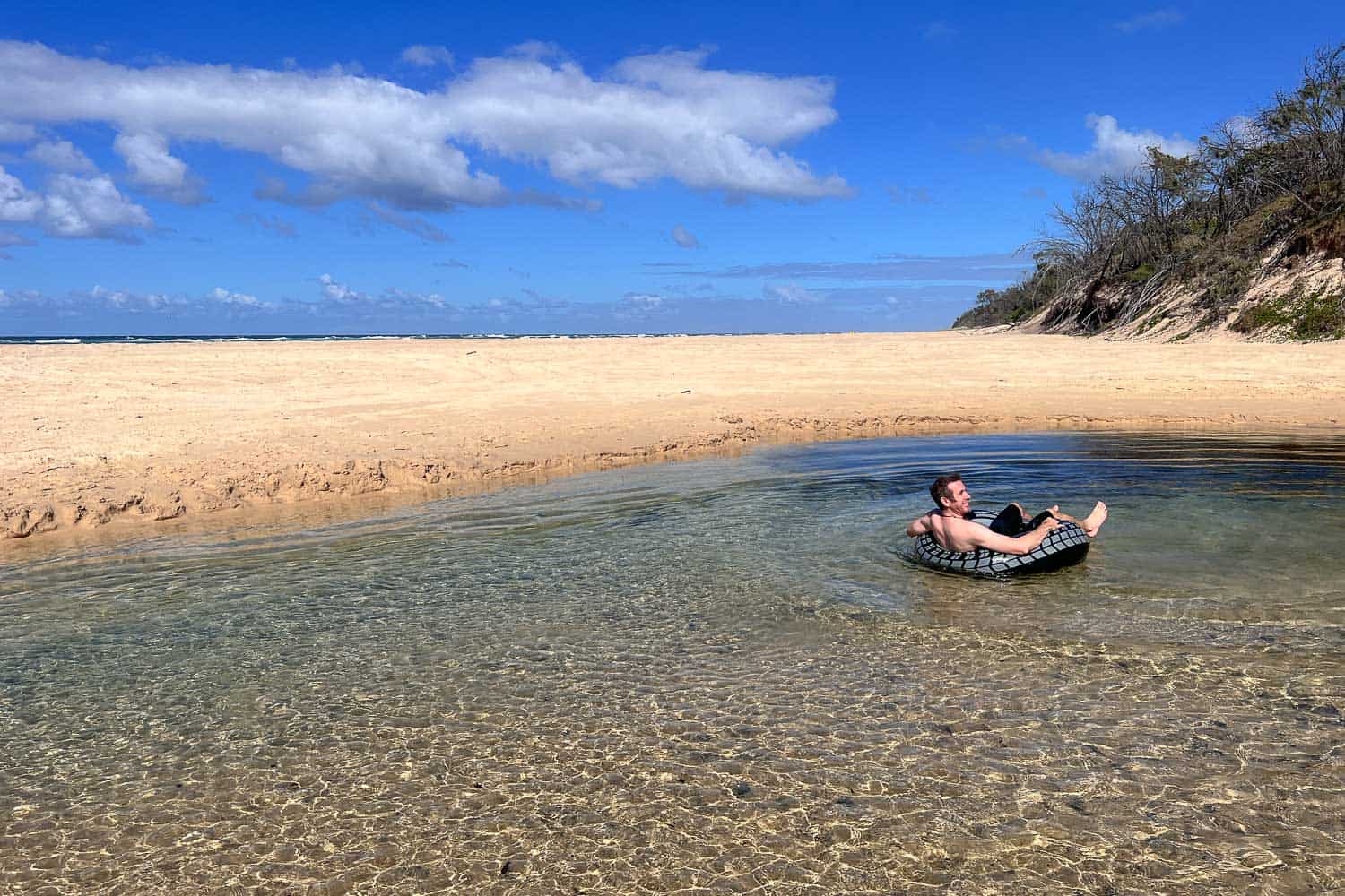 Simon tubing along Eli Creek on 75 Mile beach, K'gari, Queensland, Australia