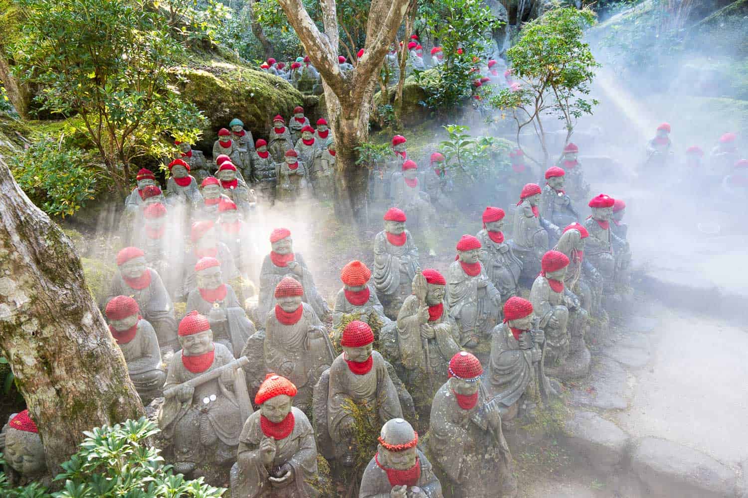 Red capped rakan statues in mist at Daishoin Temple on Miyajima Island