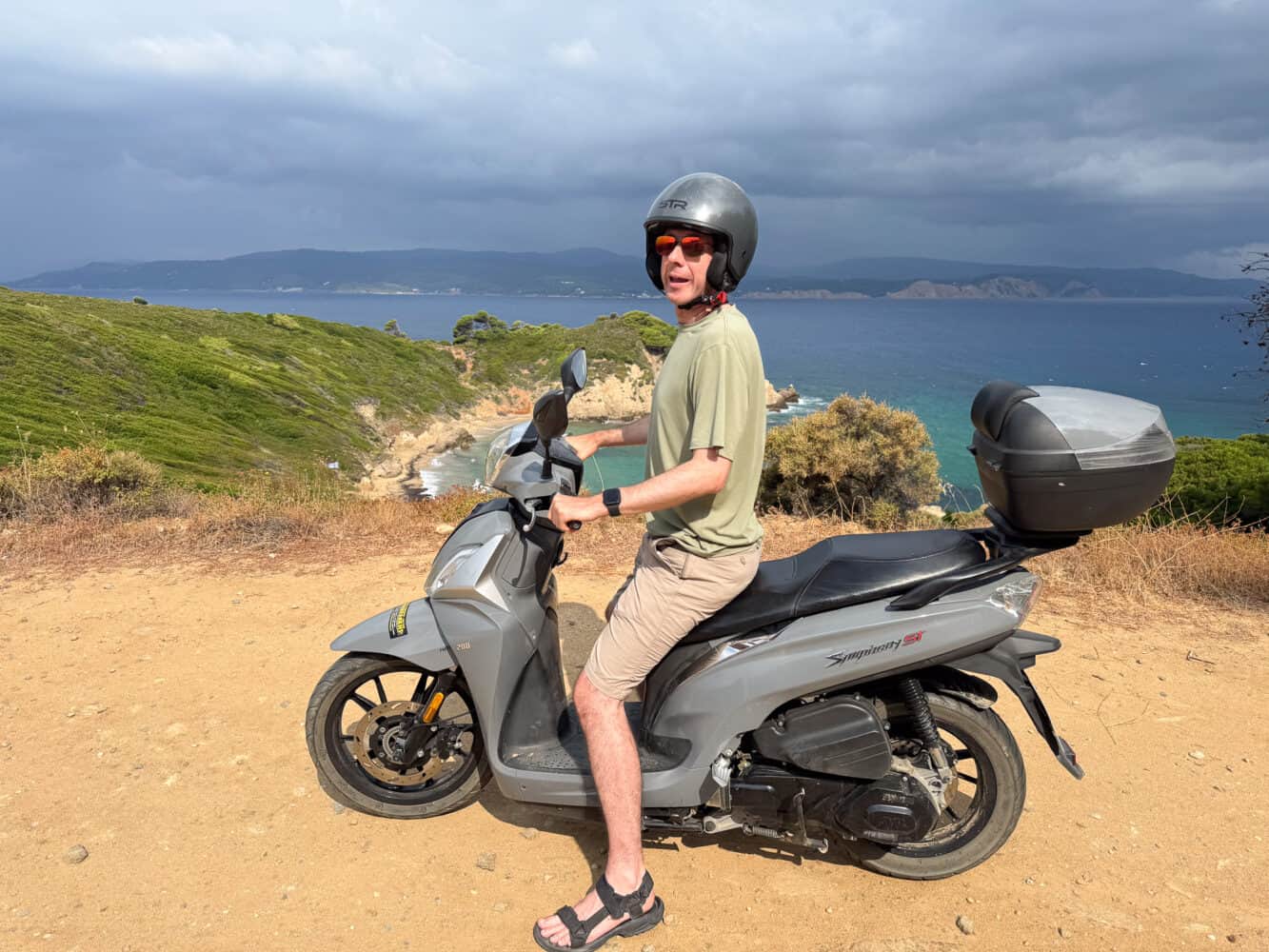 Simon riding a motorbike on the north coast of Skiathos,, Greece