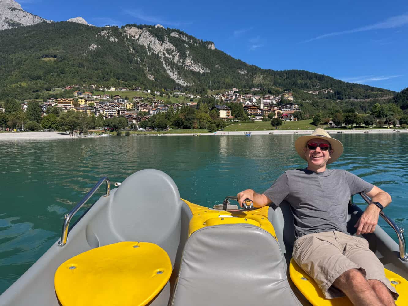 Simon in a Gogo electric boat on Lake Molveno with Molveno village behind.