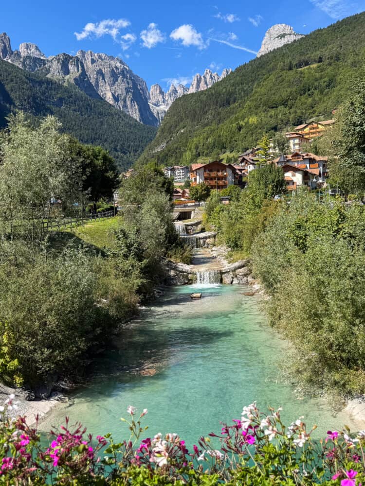 View from Ponte sul Rio Massò bridge in Molveno of turquoise river and Brenta Dolomite mountains.