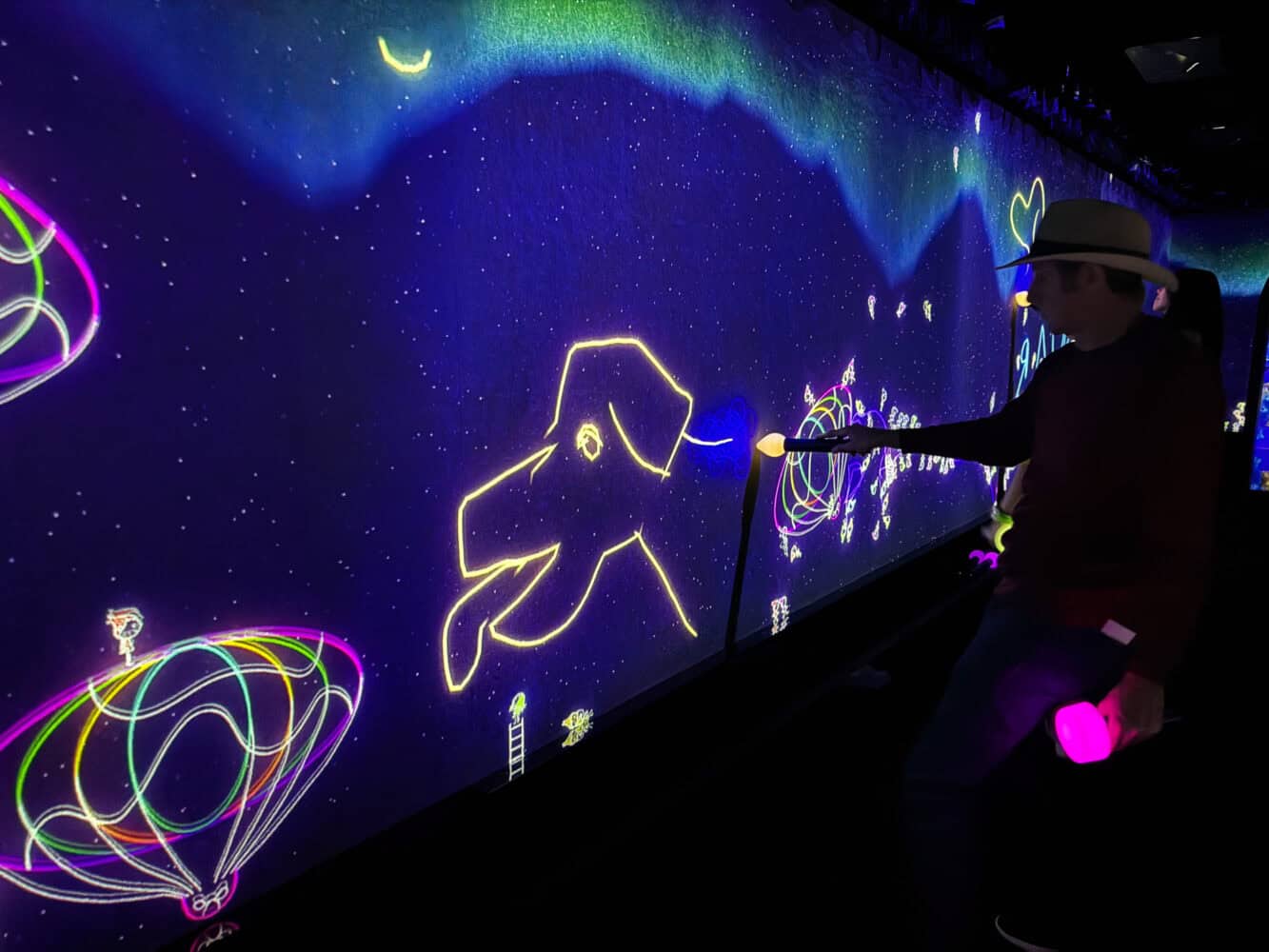 Simon drawing on wall in the Athletics Forest area of TeamLab Biovortex Kyoto.