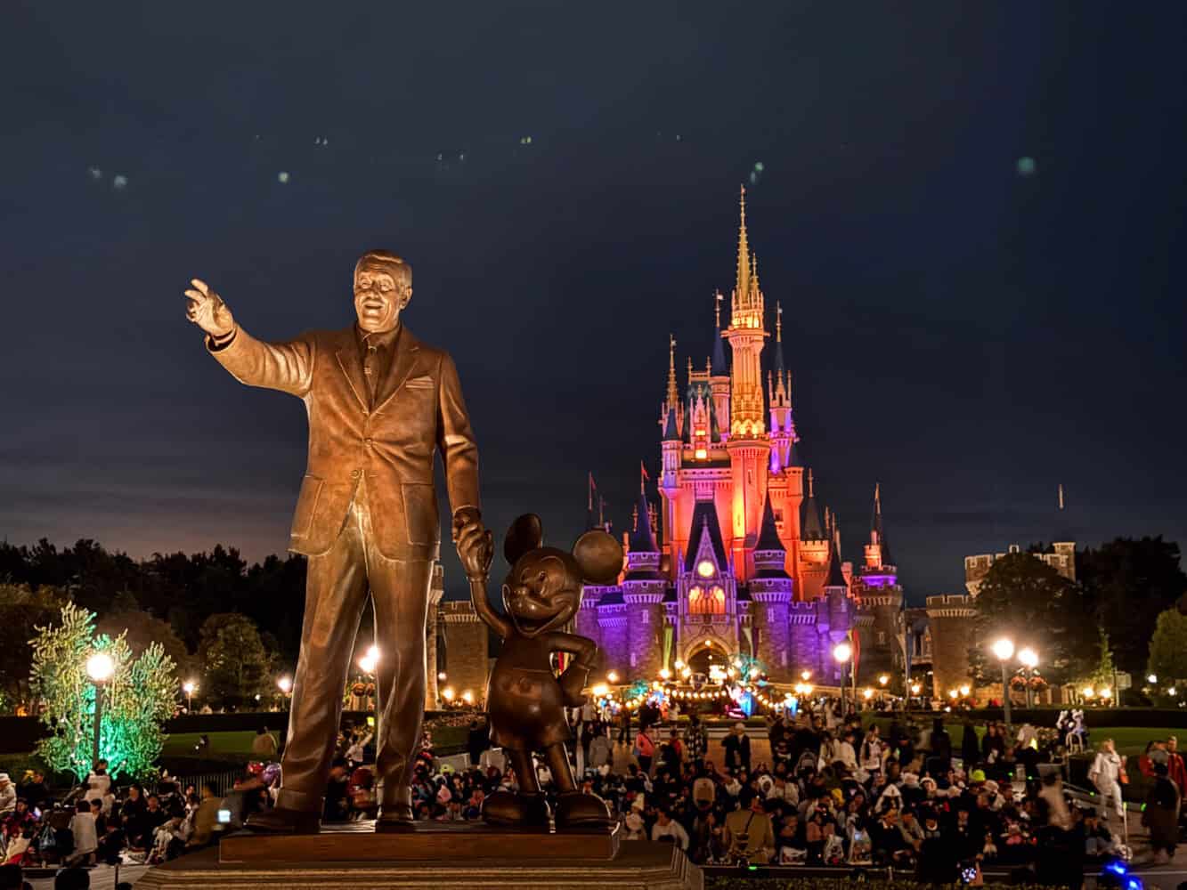 Tokyo Disneyland Walt statue and castle at night.